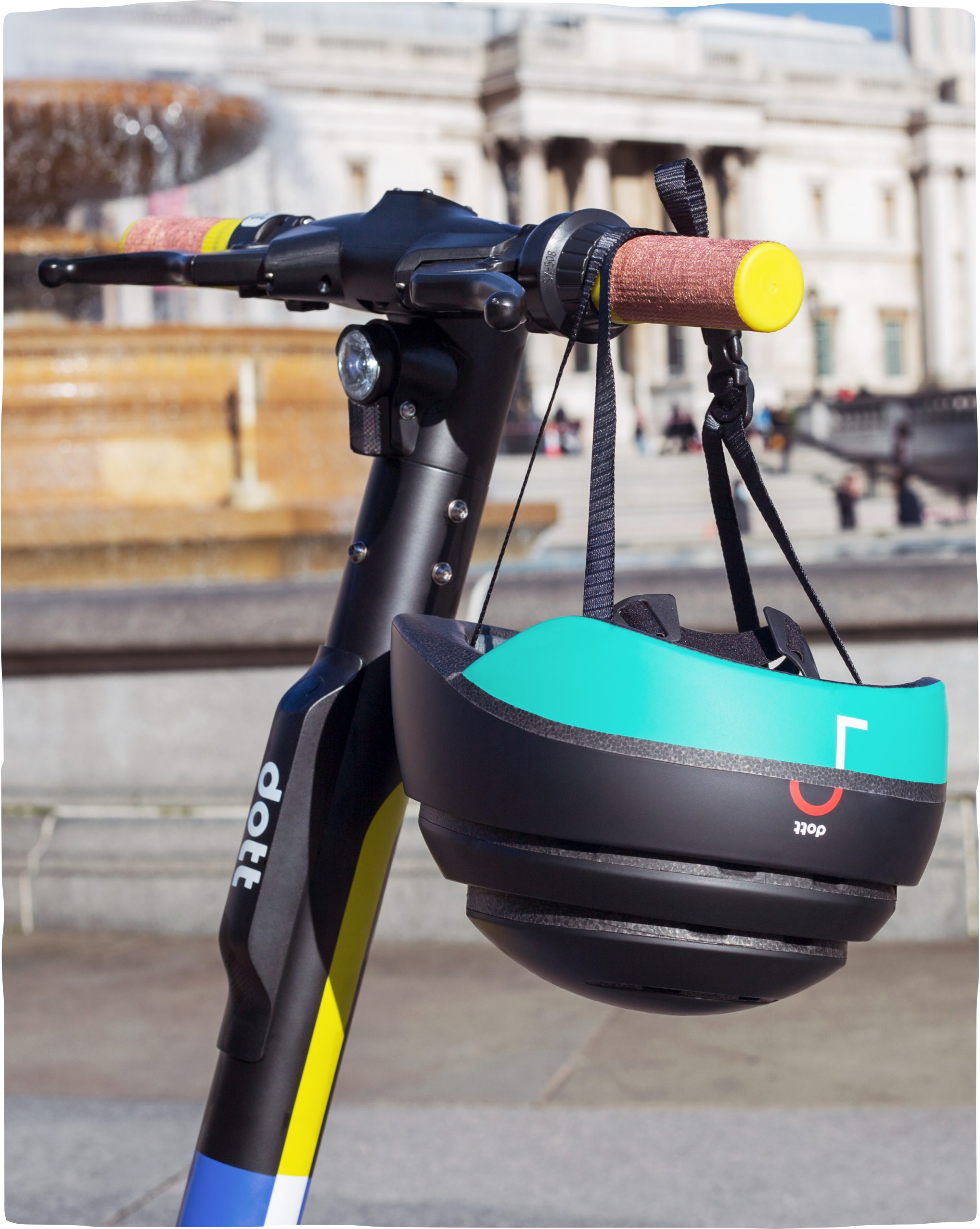 An image of a parked Dott scooter with only the handlebars in the frame. A Dott-branded helmet hangs from the handlebars.