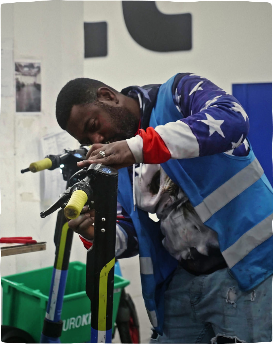 A man at a Dott warehouse workstation fixing parts of a scooter to ensure safe rides for all.